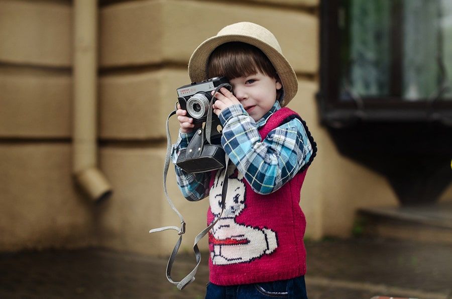 کودکی که یک دوربین عکاسی را مقابل چشم خود قرار داده است.