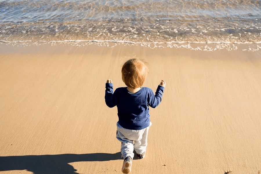 یک کودک در ساحل از نمای پشت سر